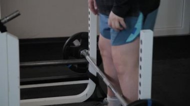 Kilolu yetişkin adam spor salonunda deadlift gerçekleştirir.