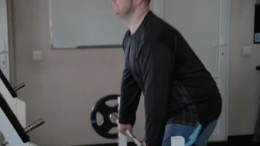 Kilolu yetişkin adam spor salonunda deadlift gerçekleştirir.