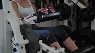 Atletik güzel kadın simülatör bacak uzantısı üzerinde gerçekleştirir.