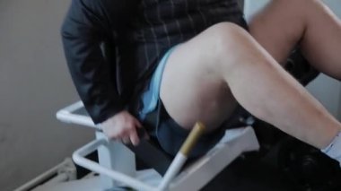 Kilolu yetişkin adam simülatörde bacaklarını presler.