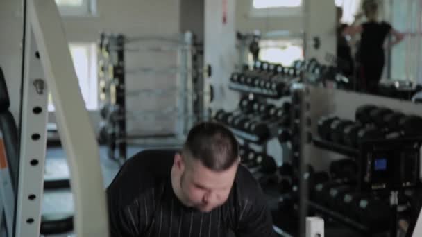 Hombre adulto con sobrepeso realiza levantamiento de pesas en el gimnasio . — Vídeo de stock