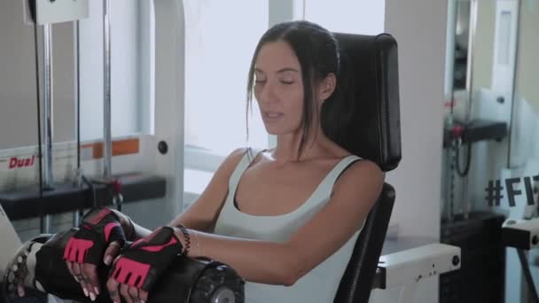 Atletische mooie vrouw presteert op de Simulator been extensie. — Stockvideo
