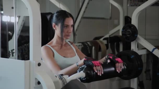 Atletik güzel kadın simülatör bacak uzantısı üzerinde gerçekleştirir. — Stok video