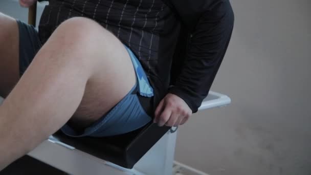 L'uomo adulto con sovrappeso preme le gambe sul simulatore . — Video Stock