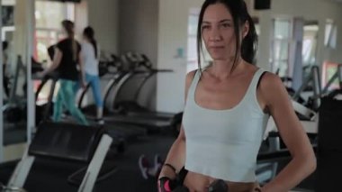 Güzel atletik kız dumbbells ile ayakta ve konuşuyor.