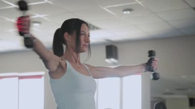 Güzel atletik kadın ayakta bir halter yapıyor.