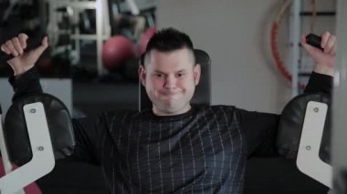 Aşırı kilolu yetişkin adam simülatör göğsünü trenler.