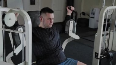 Aşırı kilolu yetişkin adam simülatör göğsünü trenler.