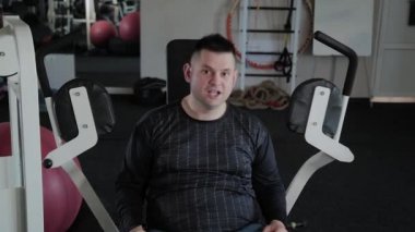 Aşırı kilolu yetişkin adam simülatör göğsünü trenler.