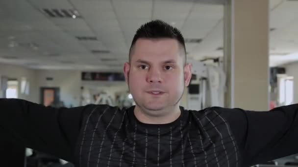 Dospělý muž s nadváhou provádí chov s činkami. — Stock video
