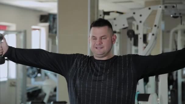 Adult man with overweight performs breeding with dumbbells. — Stock Video