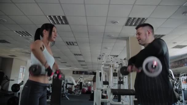 Muž s nadváhou dospělých a fitness žena společně zvednou zvony.. — Stock video