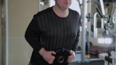 Kilolu yetişkin bir adam bir spor salonunda hiperuzantısı gerçekleştirir.