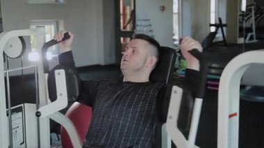 Aşırı kilolu yetişkin adam simülatör göğsünü trenler.