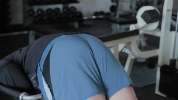Un hombre adulto con sobrepeso realiza hiperextensión en un gimnasio . — Vídeo de stock