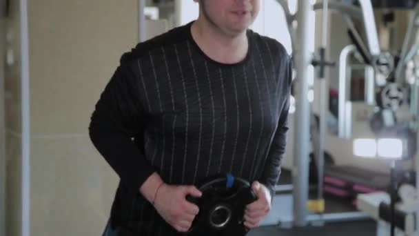 Een overgewicht volwassen man voert benadrukt in een sportschool. — Stockvideo