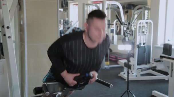 Un homme adulte en surpoids effectue une hyperextension dans une salle de gym . — Video