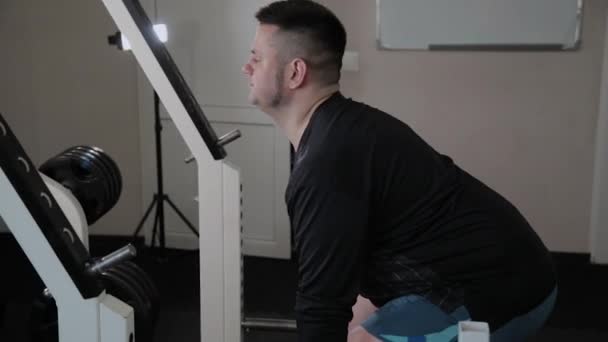 Hombre adulto con sobrepeso realiza levantamiento de pesas en el gimnasio . — Vídeos de Stock