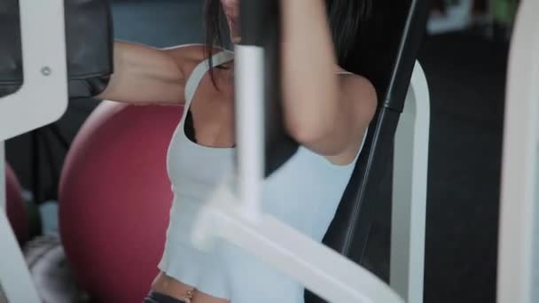 Belle femme sportive entraîne les muscles pectoraux sur le simulateur . — Video