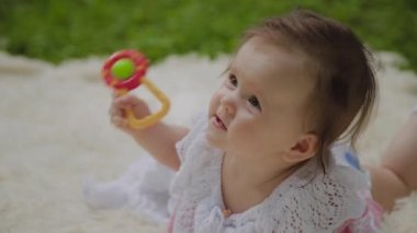 Parkta yatak örtüsü üzerinde oynayan çok küçük ve güzel bir kız.