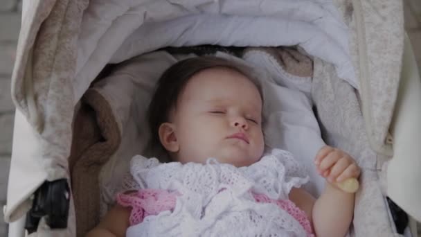 Красива маленька дівчинка спить у дитячій колясці на вулиці . — стокове відео