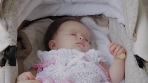 Beautiful little girl sleeping in a baby carriage on the street. — Stock Video