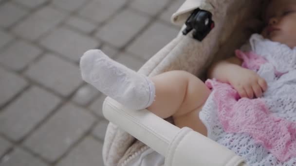 Beautiful little girl sleeping in a baby carriage on the street. — Stock Video