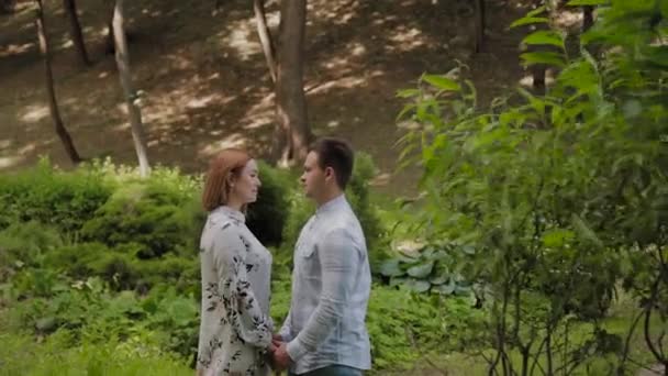 Beautiful happy young couple is embracing in the park on the alley in sunny weather. — Stock Video
