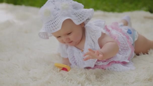 Una chica muy pequeña y hermosa jugando en la colcha en el parque . — Vídeo de stock