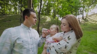 Genç anne ve baba parktaki bebekleri elleriyle besliyor..