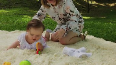 Parkta yatak örtüsü üzerinde oynayan çok küçük ve güzel bir kız.