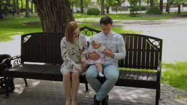 Küçük mutlu bir çocuk ailesiyle parkta bir bankta mısır çubukları yiyor..