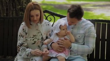 Küçük mutlu bir çocuk ailesiyle parkta bir bankta mısır çubukları yiyor..