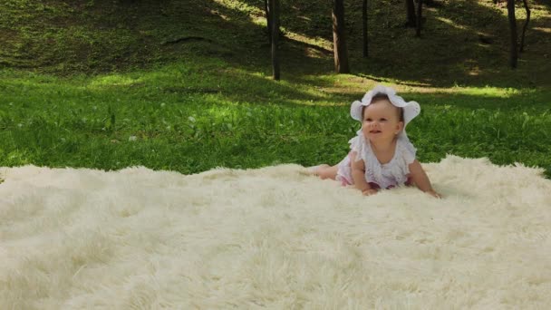 Uma menina muito pequena e bonita brincando na colcha no parque . — Vídeo de Stock