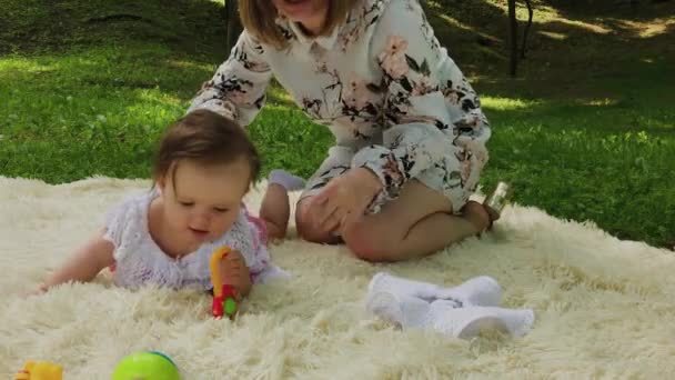 A very small and beautiful girl playing on the bedspread in the park. — Stock Video