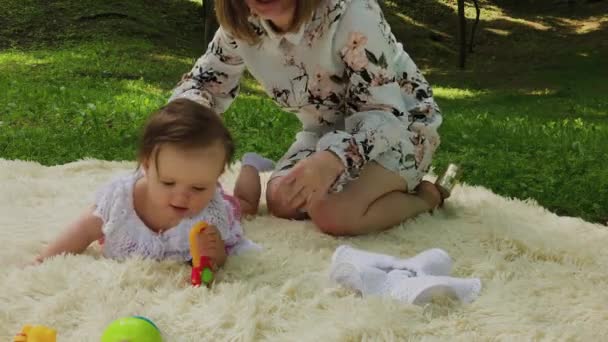 Uma menina muito pequena e bonita brincando na colcha no parque . — Vídeo de Stock