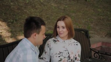 Aşık güzel mutlu çift parkta bir bankta oturan ve konuşurken.