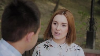 Aşık güzel mutlu çift parkta bir bankta oturan ve konuşurken.