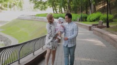 Parkta yürüyen küçük bir çocuk ile mutlu bir aile.