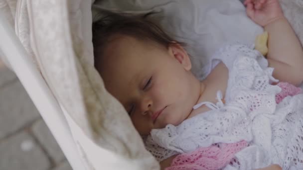Beautiful little girl sleeping in a baby carriage on the street. — Stock Video