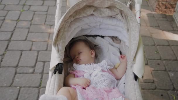 Beautiful little girl sleeping in a baby carriage on the street. — Stock Video