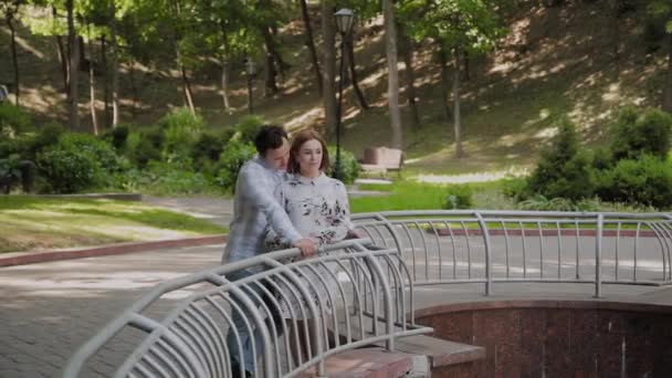Щасливі коханці присідали біля паркану фонтану . — стокове відео