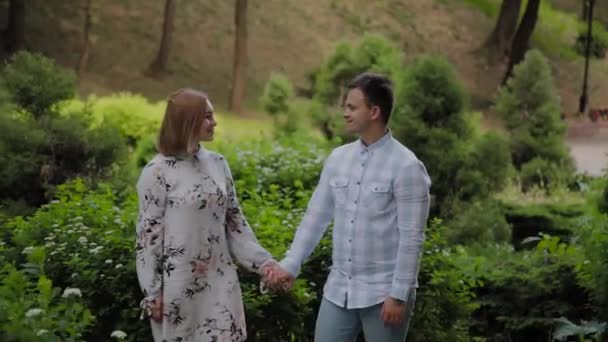 Beautiful happy young couple walking through the park in sunny weather. — Stock Video