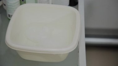 Cildin silinme için ıslak mendil hazırlama süreci. Bir güzellik uzmanın elleri yakın. Beyaz bir bardak içinde sulu solüsyon. Güzellik salonunda kozmetik prosedürü