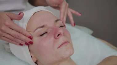 Profesyonel kozmetolojist güzellik salonunda yüz masajı yapıyor.