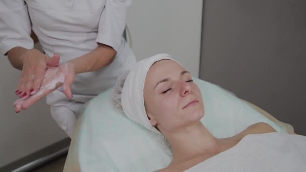 Professionele schoonheidsspecialist wrijft massage crème. — Stockvideo