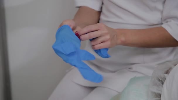 Cosmétologue professionnel porte des gants en caoutchouc bleu pour la procédure . — Video