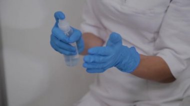 Lastik eldiven hemşire ellerinin üzerinde bir dezenfektan sprey yakın çekim. El dezenfektan çözüm üzerinde oyuncak bir hemşire.