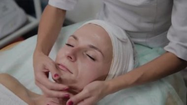 Profesyonel kozmetolojist kız yüzüne nemlendirici uygular.