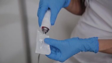 Profesyonel kozmetolojist Dermapen cihazlarına iğne koyuyor.